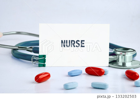 A nurses desk features a stethoscope and various colorful pills scattered around. A sign reading Nurse emphasizes the caring role in health and wellness 133202503
