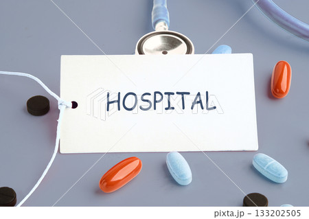 A hospital label rests among colorful pills and a stethoscope, highlighting the importance of healthcare. The scene evokes a sense of healing and wellbeing in a clinical setting A hospital label rests among colorful pills and a stethoscope, highlighting the importance of healthcare. The scene evokes a sense of healing and wellbeing in a clinical setting 133202505