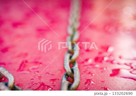 Diagonal metal chain on wet pink background 133202690