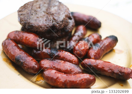 Grilled chorizos and hamburgers served on rustic plate Grilled chorizos and hamburgers served on rustic plate 133202699