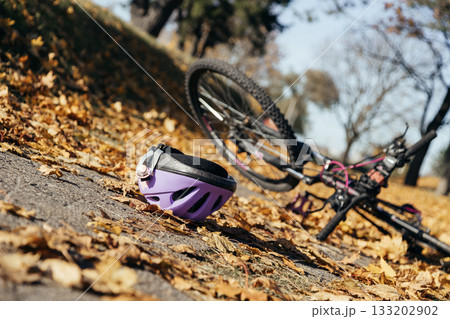 Purple helmet lies abandoned on the pavement beside a toppled bicycle, evidence of a sudden fall. 133202902