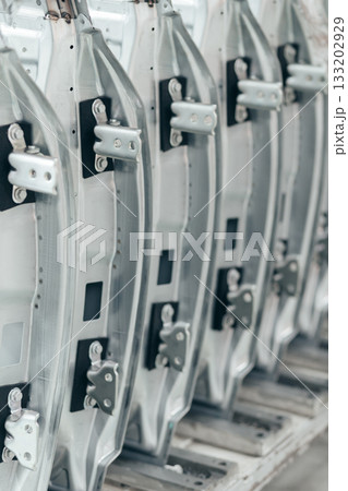 batch of unpainted metal car doors ready for car assembly in the welding shop of car assembly plant 133202929