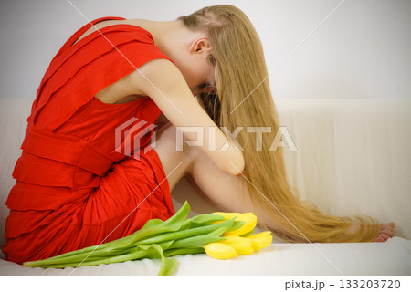 Sad elegant woman sitting on sofa with tulip Sad elegant woman sitting on sofa with tulip 133203720