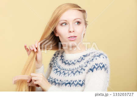 Teenage blonde girl brushing her hair with comb Teenage blonde girl brushing her hair with comb 133203727