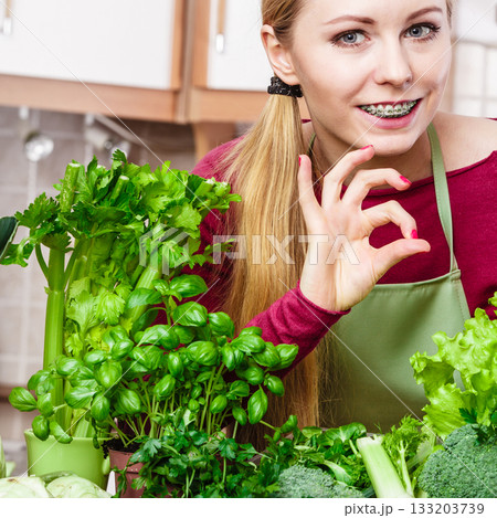 Woman in kitchen having many green vegetables 133203739