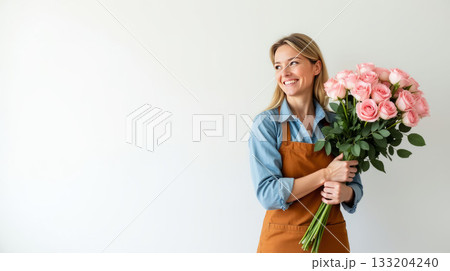 Woman in a brown apron holding pink roses, standing against a light background, radiating joy. Concept of floristry and happiness. Flower delivery concept. Copy space Woman in a brown apron holding pink roses, standing against a light background, radiating joy. Concept of floristry and happiness. Flower delivery concept. Copy space 133204240