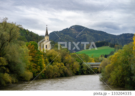 Panoramic view of the church spire among the autumn city against the background of the Austrian Alps and the river Panoramic view of the church spire among the autumn city against the background of the Austrian Alps and the river 133204335