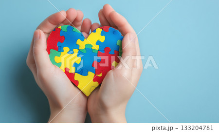 World autism awareness day concept. Child hands holding colorful puzzle heart on blue background 133204781