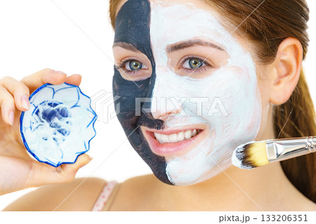 Girl black mask on half face apply white mud Girl black mask on half face apply white mud 133206351