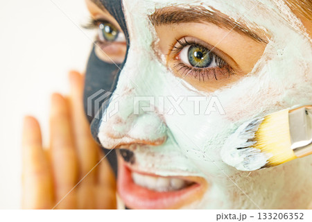 Female applying green mud facial mask Female applying green mud facial mask 133206352