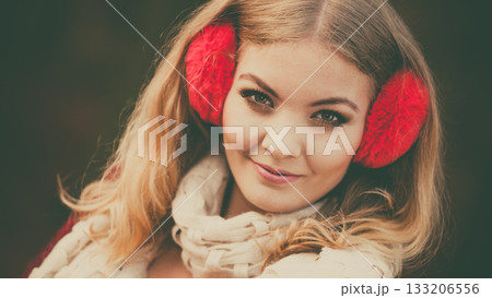 Portrait of pretty smiling woman in red earmuffs. 133206556