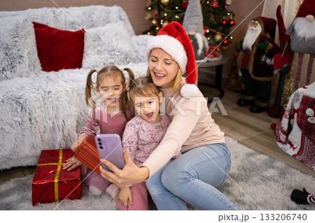 Mother and daughters taking selfie with Christmas presents 133206740