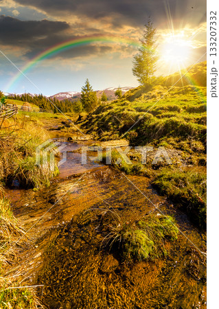 rural scene of mountain landscape in spring at sunset. green countryside with forested hills in evening light. beautiful valley sustainable development under rainbow 133207332