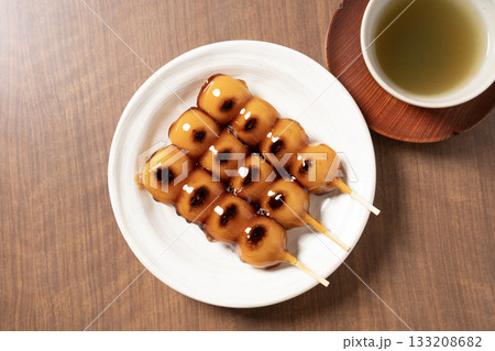 白い皿にのったみたらし団子とお茶 133208682