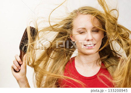 Blonde girl long blowing hair holds natural bristles brush 133208945