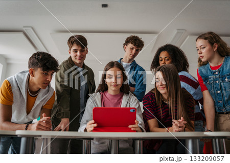 Teen students learning together with digital tablet in modern classroom. 133209057