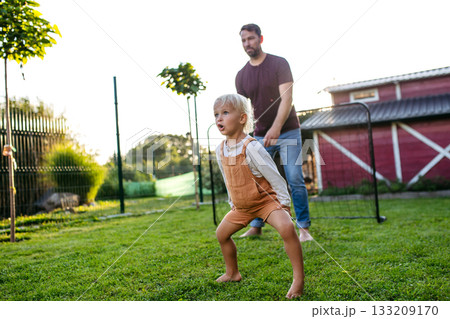 Little boy playing football with father in backyard. Little boy playing football with father in backyard. 133209170