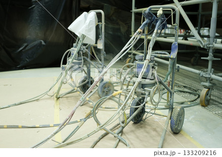Equipment used for spraying paint in a construction area with hoses and protective coverings present 133209216