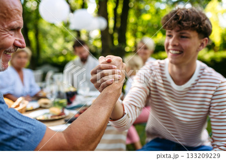 Grandson greeting his grandfather during garden party. Grandson greeting his grandfather during garden party. 133209229