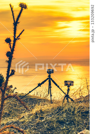 Camera taking picture film of sunrise over sea surface Camera taking picture film of sunrise over sea surface 133209692