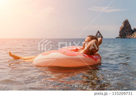 Woman Float Beach Relaxation: Woman relaxes on a pink float in the ocean on a sunny day. Woman Float Beach Relaxation: Woman relaxes on a pink float in the ocean on a sunny day. 133209731