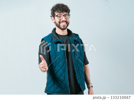 Friendly handsome guy greets you with open hand isolated. Male person extending her hand to the camera welcoming you 133210087