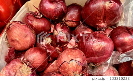 Pile of an large red onion sale in box in vegetable stand display at supermarket show organic food, vegetarian food, healthy food. Close-up. 133210228