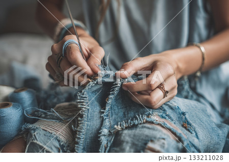 A person repairing torn clothes with a sewing kit, embracing sustainable fashion and slow living. A person repairing torn clothes with a sewing kit, embracing sustainable fashion and slow living. 133211028