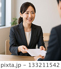 書類を手渡す女性ビジネスパーソン（Businesswoman Handing a Document） 133211542