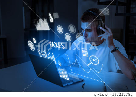 Young man working on tax calculations with virtual data visualization at home 133211786