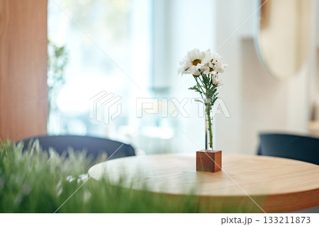 Bright flowers in a vase on a wooden table in a cozy cafe setting during the afternoon Bright flowers in a vase on a wooden table in a cozy cafe setting during the afternoon 133211873