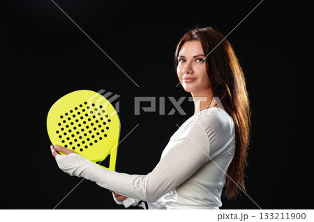Brightly lit woman holding a paddle ready for a game in a studio setting 133211900