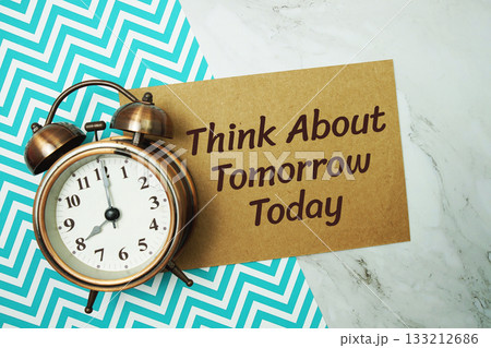Think about Tomorrow Today text written on paper card with alarm clock on marble background 133212686