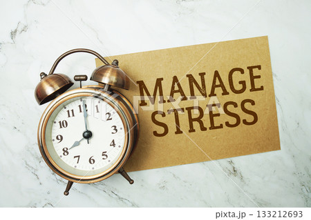 Manage Stress text written on paper card with alarm clock on marble background Manage Stress text written on paper card with alarm clock on marble background 133212693
