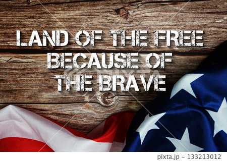 Land of the Free Because of the Brave text message with USA flag on wooden background Land of the Free Because of the Brave text message with USA flag on wooden background 133213012