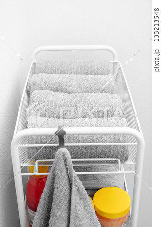 A white shelf holds neatly stacked gray towels. A white shelf holds neatly stacked gray towels. 133213548