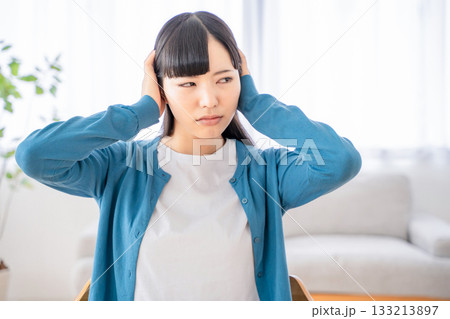 耳を塞ぐ若い女性 133213897