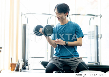 トレーニングジムでダンベルを使って筋トレする若い男性 トレーニングジムでダンベルを使って筋トレする若い男性 133213998