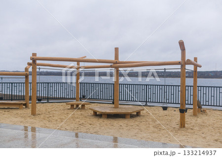 Wooden Playground on the embankment on a cloudy day in winter. Wooden Playground on the embankment on a cloudy day in winter. 133214937