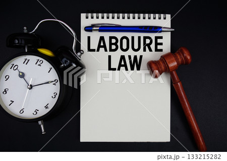 Labour Law text written on notepad with gavel and alarm clock on black background 133215282