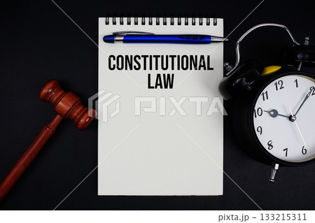 Constitutional Law text written on notepad with gavel and alarm clock on black background 133215311