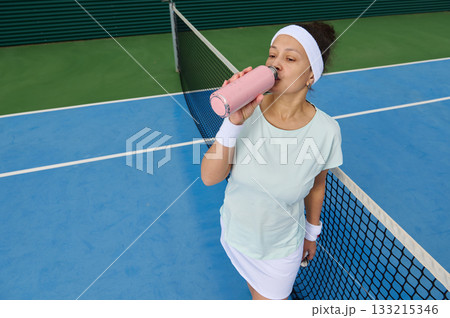 Athletic Woman Drinking Pink Smoothie On Tennis Court During Practice 133215346