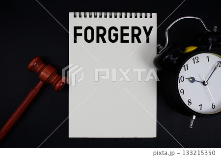 Forgery text written on notepad with gavel and alarm clock on black background Forgery text written on notepad with gavel and alarm clock on black background 133215350