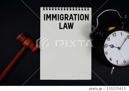 Immigration Law text written on notepad with gavel and alarm clock on black background Immigration Law text written on notepad with gavel and alarm clock on black background 133215413