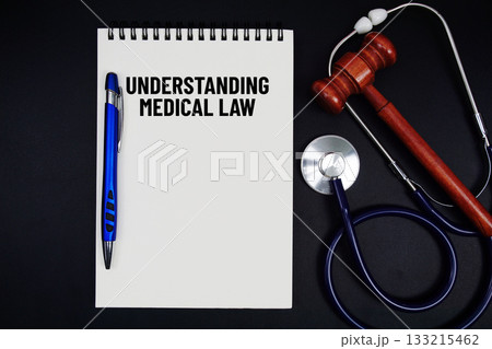 Notepad with "Understanding Medical Law" a pen, gavel, and stethoscope on a black background 133215462