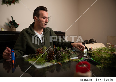 Man Crafts Holiday Centerpiece With Pinecones At Home Christmas Table 133215516