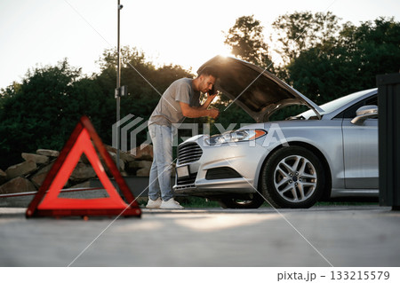 Under the sunlight, red sign, accident, broken automobile, repair. Man is with his car outdoors 133215579