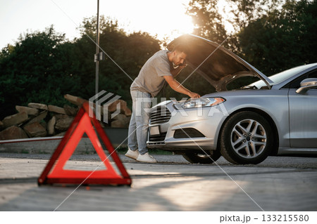 Under the sunlight, red sign, accident, broken automobile, repair. Man is with his car outdoors 133215580
