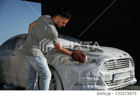 White soap and foam, washing the automobile. Man is with his car outdoors 133215673