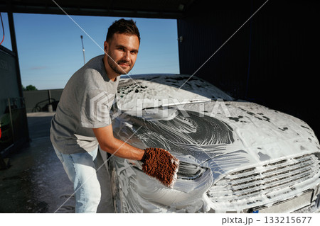 White soap and foam, washing the automobile. Man is with his car outdoors White soap and foam, washing the automobile. Man is with his car outdoors 133215677